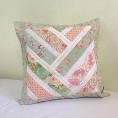 a decorative pillow made out of patchwork and quilted fabric on a white bed