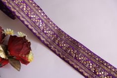 a bouquet of flowers sitting next to a purple and gold ribbon on top of a table