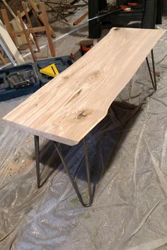 a wooden table sitting on top of a hard wood floor next to a pile of tools