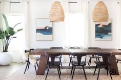 the dining room table is surrounded by black chairs and rattan pendant lights hanging from the ceiling