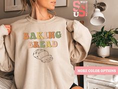 a woman wearing a sweatshirt with the words baking bread on it in front of her