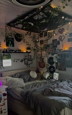 an unmade bed in a room with plants growing on the wall and lights hanging from the ceiling