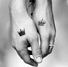 two people holding hands with tattoos on their fingers, one has a crown and the other has a diamond