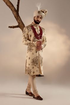 Frosted Almond Sherwani Set | Jatin Malik Introducing our masterpiece: the golden placement hand-embroidered sherwani. This exquisite sherwani showcases an intricate embroidery technique that utilizes various types of dabka and moti, creating a stunning visual impact. Paired with a wine hand-embroidered stole and matching safa, this ensemble epitomizes refined luxury and traditional excellence. Perfect for making a grand and elegant statement, this sherwani set is a testament to exceptional craftsmanship and timeless style. Included in purchase: Sherwani, Kurta, Churidar, Stole, Safa Product Specification Color: Golden Fabric: Linen silk Occasion: Engagement, Wedding, Bridal, Reception Style: Sherwani, Kurta, Churidar, Stole, Safa Care: Dry Clean Work: Hand Embroidery Customization options Jatin Malik, Embroidered Sherwani, Blouse Yoke, Dhoti Pants, Haldi Ceremony, Indian Groom, Royal Look, Indian Man, Groom Outfit