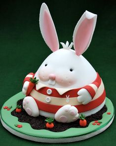 a cake shaped like a bunny sitting on top of a green plate with carrots