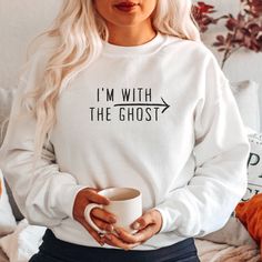 "Looking for a cozy sweatshirt that shows off your love for all things paranormal? Look no further than our I'm with the ghost sweatshirt! This comfy crewneck is perfect for getting cozy by the fire on a chilly evening or taking a walk on a crisp fall day. The simple design features the words \"I'm with the ghost\" in black against a white background, letting everyone know where your allegiances lie. Whether you're a fan of ghost stories, horror movies, or just enjoy dressing up for Halloween, t Halloween Sweatshirts Cricut, Halloween White Screen Print Sweatshirt, Cute Cotton Halloween Sweatshirt, Spooky Sweatshirt For Fall, Hooded Spooky Halloween Sweatshirt, Fall Sweatshirt Outfit, Comfy Crewneck, Spooky Sweatshirt