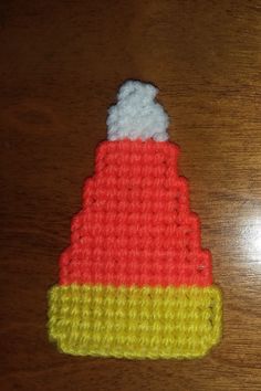 a crocheted hat with a white and yellow stripe on it sitting on a wooden table