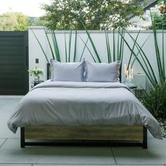 a bed sitting in the middle of a bedroom next to a lush green plant filled wall