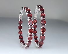 A pair of red garnet gemstone sterling silver hoop earrings.  Watch a video of this item Hoop Size: 37mm Metal: Sterling Silver Gemstone:  Garnet Closure: hinge post Red Hoop Fine Jewelry, Fine Jewelry Red Hoop Earrings, Formal Gemstone Hoop Jewelry, Red Hoop Jewelry For Formal Occasions, Modern Garnet Jewelry For Anniversary, Sterling Silver Hoop Jewelry, Aaa Quality Sterling Silver Hoop Jewelry, Red Gemstone Hoop Earrings, North Hills