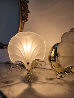 two lamps sitting on top of a marble counter next to a mirror and lamp shade