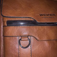 A faux brown leather bag with the look and feel of real leather. A nice bag for business or school to carry many of your essential items , including a tablet and your cell phone . It's made by the company Weixier, established in 2008. This bag is brand new without tags with a large top opening that zippers. There are front and back zippers and a pocket that snaps closed. A long canvas strap to throw over your shoulder or a convenient handle for a quick carry. An awesome useful bag for men and their daily needs, and don't forget snacks! Faux Leather Satchel With Mobile Phone Bag For Travel, Travel Faux Leather Satchel With Mobile Phone Bag, Faux Leather Travel Satchel With Phone Bag, Faux Leather Travel Satchel With Mobile Phone Bag, Brown Crossbody Shoulder Bag For School, Brown Faux Leather School Bag, Business Faux Leather Shoulder Bag With Phone Pocket, Business Briefcase With Cell Phone Pocket And Crossbody Shape, Brown Satchel With Cell Phone Pocket For Daily Use