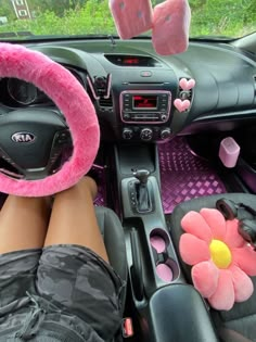 the interior of a car is decorated with pink flowers and plush animal ears, while someone's feet are propped up on the steering wheel