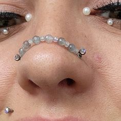 a close up of a person with some piercings on their nose and eye lashes