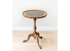 a small wooden table with a glass top on it's legs and an ornate base