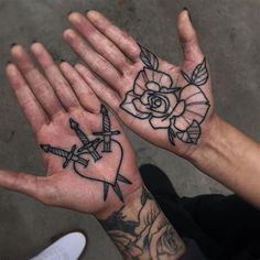 two hands that have tattoos on them with roses and swords in the middle one hand