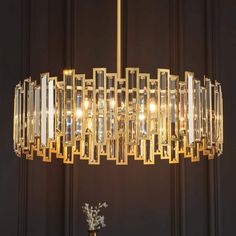 a chandelier hanging from the ceiling in front of a black wall and vase with flowers