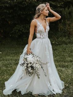 a woman in a white wedding dress holding a bouquet and posing for the camera with her hand on her head