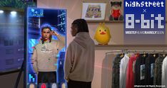 a man standing in front of a display case with clothes on it and an emo chick doll next to him