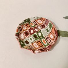 a ceramic plate with an abstract design on it sitting next to a green leafy plant