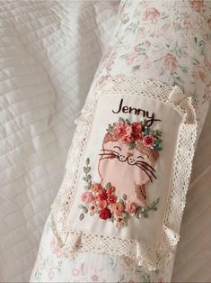 an embroidered pillow with a cat on it's back and name jenny in the middle