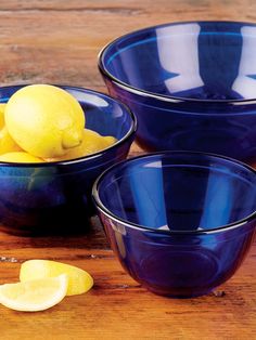 three bowls filled with lemons on top of a wooden table next to sliced lemons