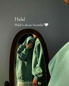 a person standing in front of a mirror looking at their cell phone while wearing a green hoodie