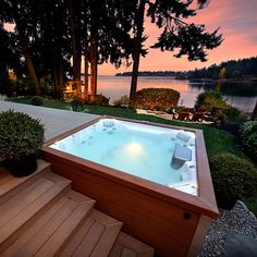 a hot tub sitting on top of a wooden deck next to a body of water