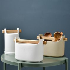 three white containers with wooden spoons on a table