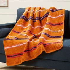 a blue couch with an orange blanket on it