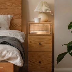 a bed with a wooden headboard and night stand next to a potted plant