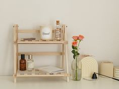 a wooden shelf with bottles, candles and flowers on it next to a vase filled with roses