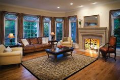 a living room with couches, chairs and a fire place in the center area