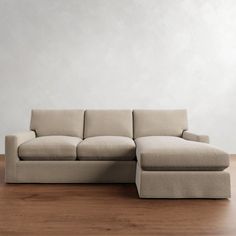 a beige sectional couch sitting on top of a wooden floor next to a white wall