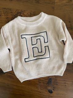 a white sweater with the letter f on it