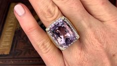 This impressive Alexandro Devitta designed ring is centered with one (1) cushion mixed cut natural amethyst set into a four-prong setting. The top of each prong is bezel set with one (1) round brilliant cut diamond. The center stone is bordered with twenty-six (26), bead set, round brilliant cut diamonds. The shoulders of the ring are each accented with twenty-seven (27), bead set, round brilliant cut diamonds. One side face of the ring features a white gold plate signed Alexandro Devitta and is Elegant Cushion Cut Yellow Gold Amethyst Ring, Luxury Rectangular Amethyst Ring, Luxury Amethyst Cushion Cut Ring For Formal Events, Luxury Amethyst Cushion Cut Ring For Formal Occasions, Luxury Cushion Cut Amethyst Ring For Formal Occasions, Luxury Cushion Cut Amethyst Ring For Anniversary, Luxury Purple Cushion Cut Jewelry, Formal Amethyst Cushion Cut Ring With Accent Stones, Formal Amethyst Cushion Cut Rings