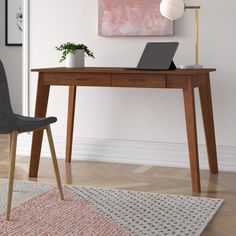 a laptop computer sitting on top of a wooden desk next to a chair and rug