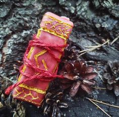 a red and yellow candle sitting next to some pine cones