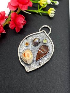 "Artisan Amber with Mexican Fire Opal pendant in sterling silver Hand-made Sterling Silver 925 Stones used: Baltic Amber, Mexican Fire Opal Purple Pearl, Peridot, Citrine Height - 2\", Width - 1 3/8\" Unique Handcrafted One-of a-kind Design Pendant Each Piece of Jewelry in my Collection is Absolutely One of a Kind! When you start wearing a piece of my jewelry you will fall in love with it more and more each day and feel that good Energy and Love that I pass into it while creating this piece of A Nature-inspired Freeform Silver Jewelry, Artisan Sterling Silver Freeform Jewelry, Sterling Silver Multi-stone Oval Pendant Jewelry, Artisan Silver Pendant Gemstones, Artisan Sterling Silver Pendant Gemstones, Sterling Silver Multi-stone Pendant Gemstones, Unique Sterling Silver Pendant Gemstones, Hand Forged Amber Sterling Silver Jewelry, Sterling Silver Multi-stone Pendant