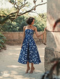 a woman in a blue dress standing next to a pillar