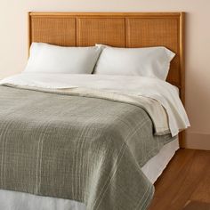 a bed with white sheets and pillows on top of wooden headboard in a bedroom