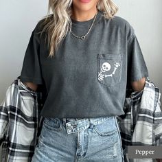 Looking for a cute halloween or fall shirt? You've come to the right place! These cute skeleton pocket tees are a great choice if you're going trick or treating or celebrating spooky season! Our unisex tees are very cute and comfy! You can pair them with your favourite leggings, tuck them into your jeans, or tie them up in a knot. We love this casual style and know you will too! MATERIALS AND SIZING These unisex tees are made with 100% soft cotton and excellent quality print. They fit nice and l Edgy Fall Tops With Pockets, Edgy Tops With Pockets For Fall, Casual Skull T-shirt For Fall, Fall Crew Neck T-shirt With Pockets, Cute Fall Tops With Pockets, Fall Skull Print Short Sleeve Tops, Cute Crew Neck Top With Pockets, Trendy Crew Neck T-shirt With Pockets, Nice Shirts For Women