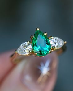 an emerald and diamond ring with three pear shaped diamonds