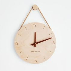 a wooden clock hanging from a rope on a white wall with the words enjoy your time