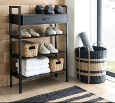 a shelf with baskets and shoes on it next to a window in a living room