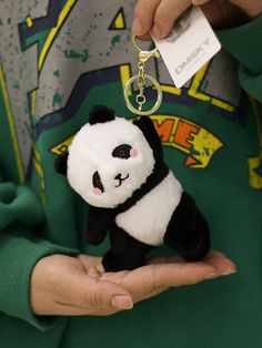 a person holding a small stuffed panda bear in their hand with a tag on it