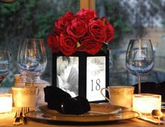 an image of a table setting with candles and red roses on the centerpieces