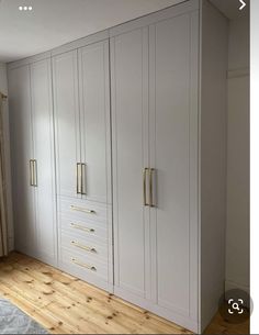 an empty room with white cabinets and wood floors