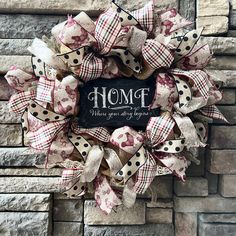 a wreath with the words home is where you are hanging on a brick wall in front of a door