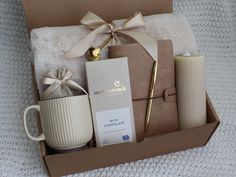 a gift box with coffee, candles and other items in it sitting on a bed