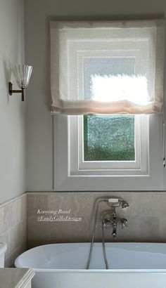 a bath tub sitting under a window in a bathroom